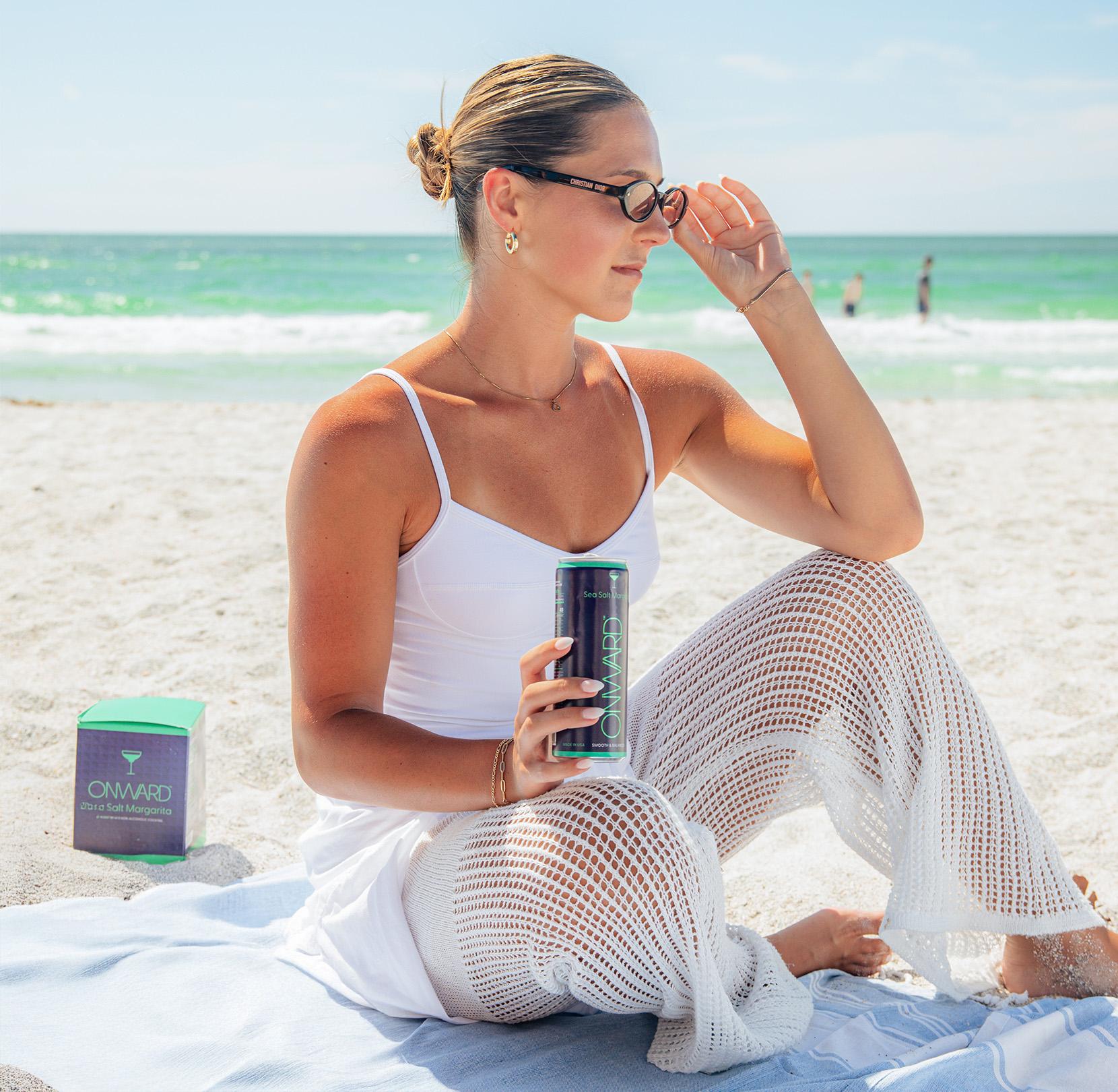 Woman on a beach drinking Onward
